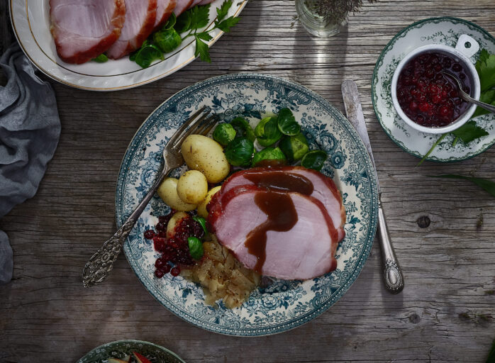 Skinkestek med brun saus, poteter og rosenkål på en tallerken.